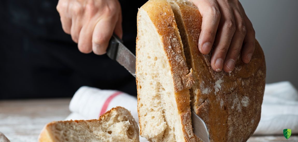 Mężczyzna kroi chleb używając dużego noza kuchennego